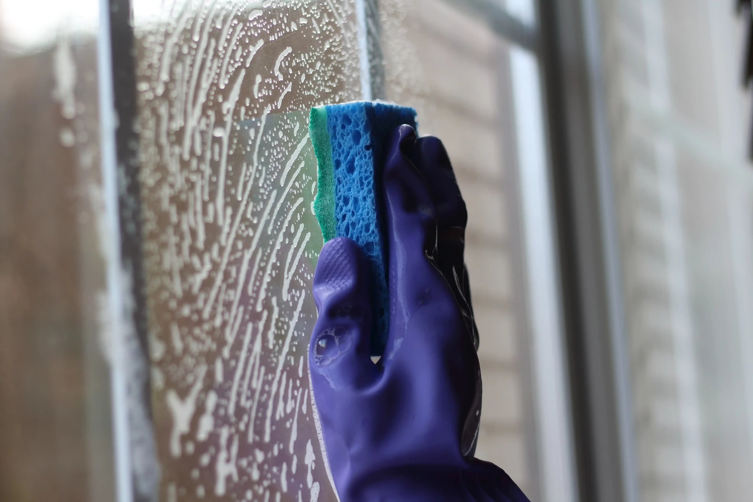 gloved hand cleans window with sponge and soap 2026 03 17 21 46 54 utc scaled
